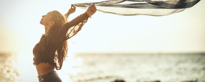 freedom from addiction _ crack cocaine rehab A woman on a beach with her arms raised after completing crack cocaine rehab - Step By Step Recovery